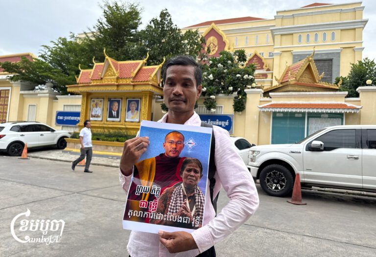 An activist holds a portrait of defrocked monk Chea Vuthy outside the Phnom Penh Municipal Court after he was sentenced to 18 months in prison. Aug. 19, 2026. (CamboJA/Try Thaney)